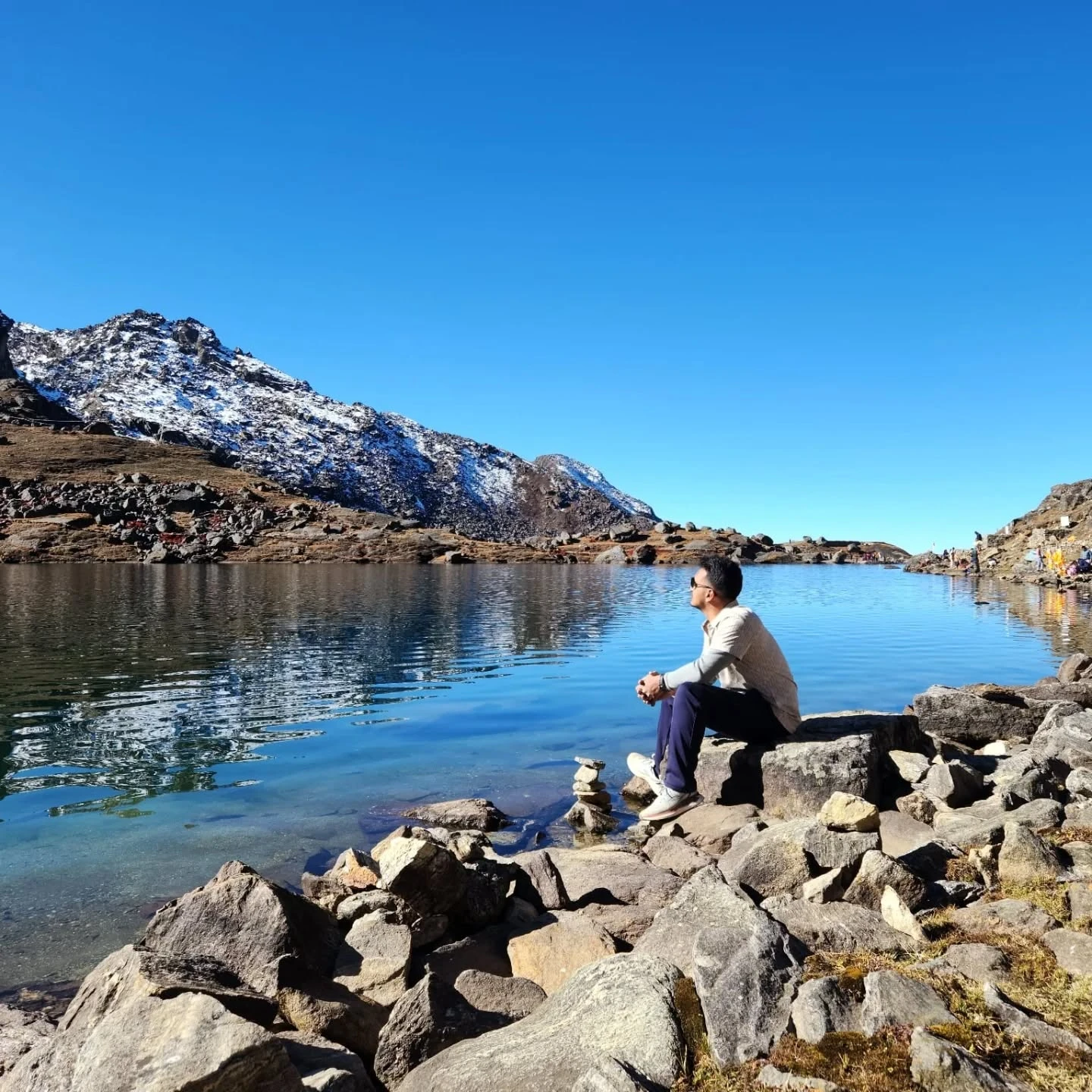Kushal Pathak sitting by an alpine lake in the Nepal Himalaya